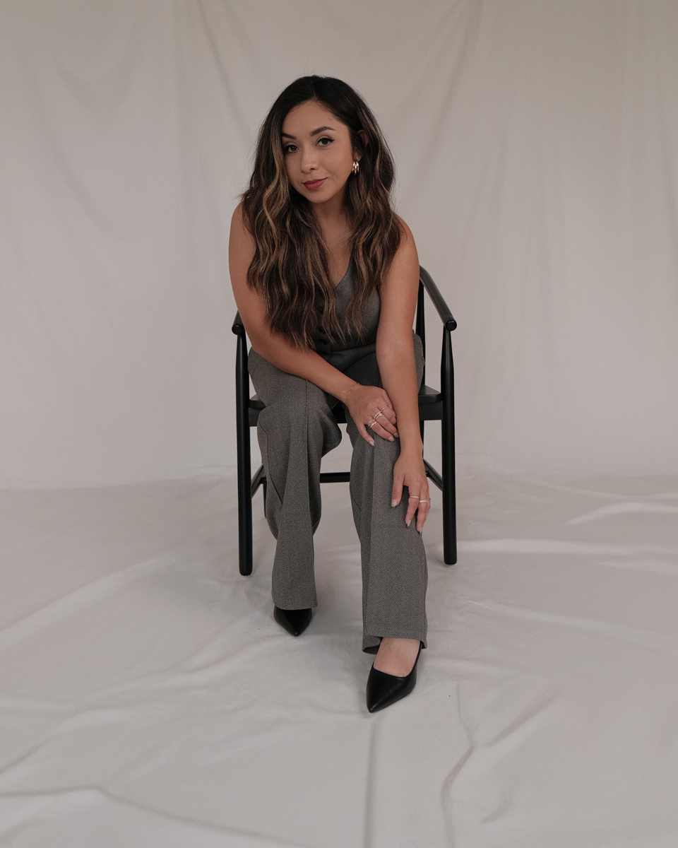 Joanna Idaly, hairstylist, seated on a black chair